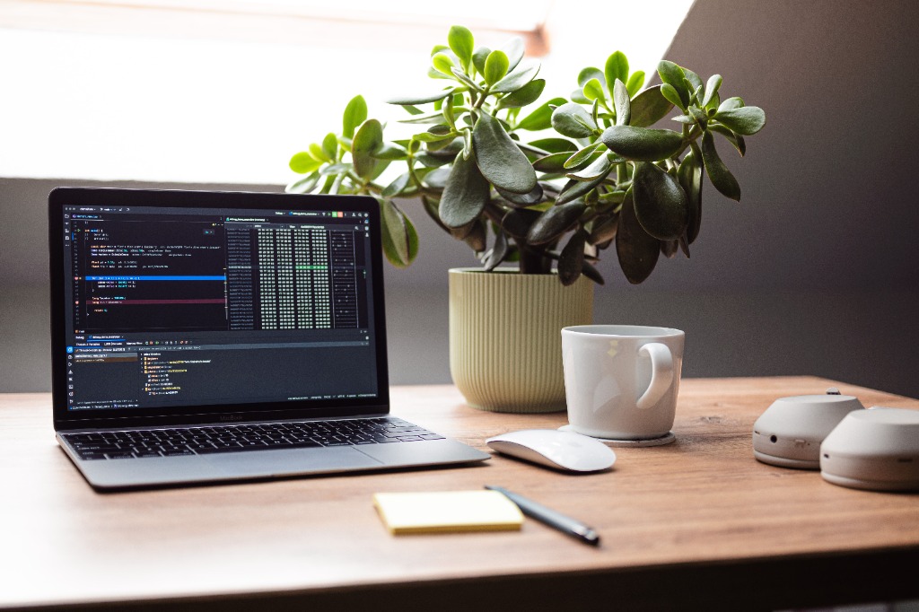 Secretária de trabalho com portátil, planta e café